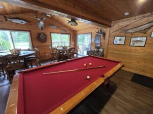 a red felted pool table set up and ready to be used in a fishing lodge