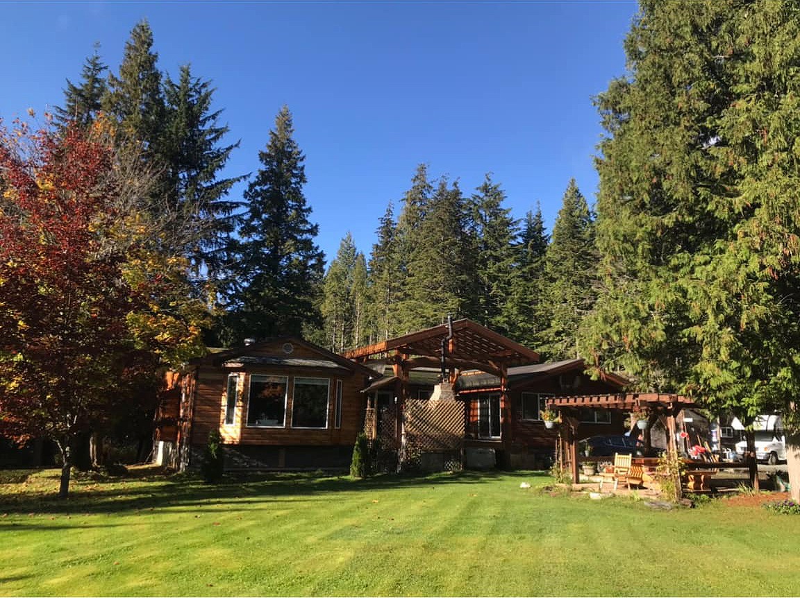 A fishing lodge sits amid a background of forest and blue skies. A wood gazebo sits to the right.